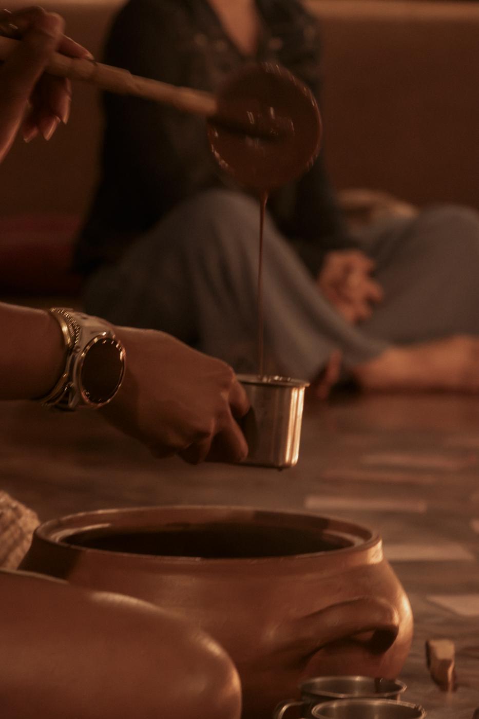 Ale sirviendo cacao ceremonial en una taza de metal