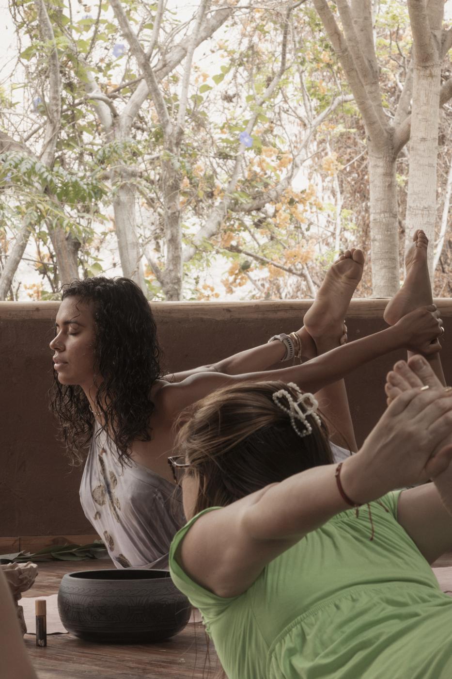 Ale en postura de yoga en un espacio de adobe rodeado de árboles